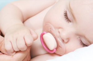 תינוק ישן עם מוצץ בתוך הפה
